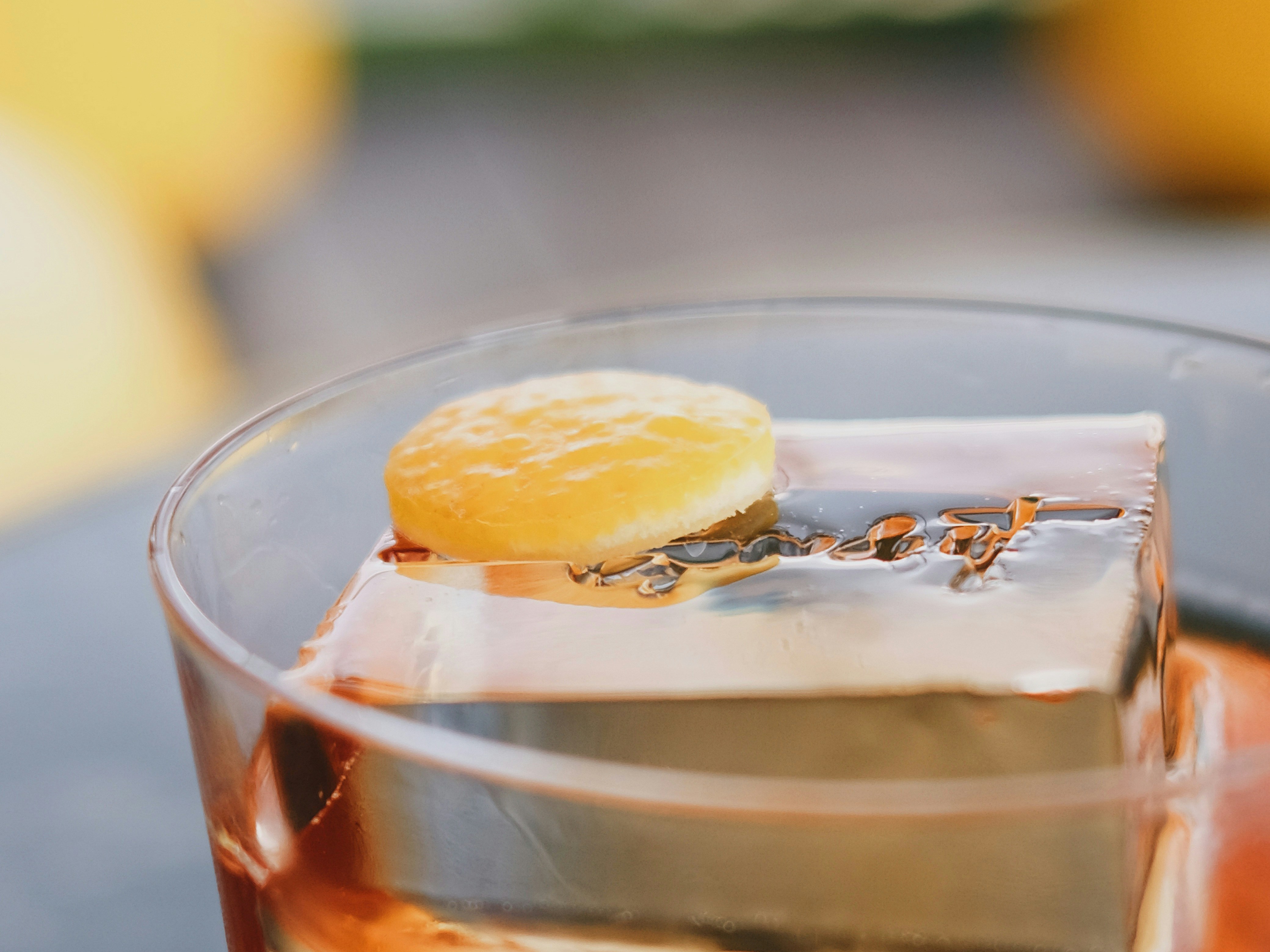 Old fashioned cocktail with branded ice cube and citrus garnish