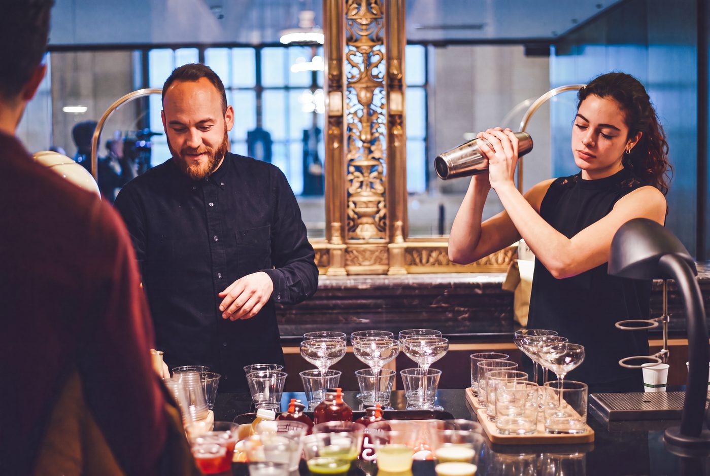 Bartenders shaking a cocktail behind the bar