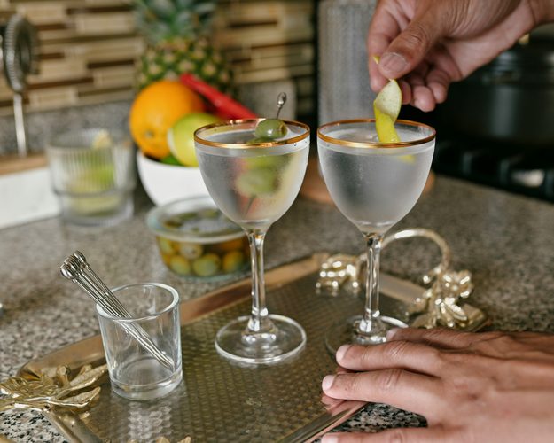 Two martinis being garnished at a bar