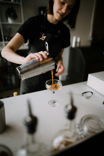 Bartender pouring a cocktail into a coupe glass