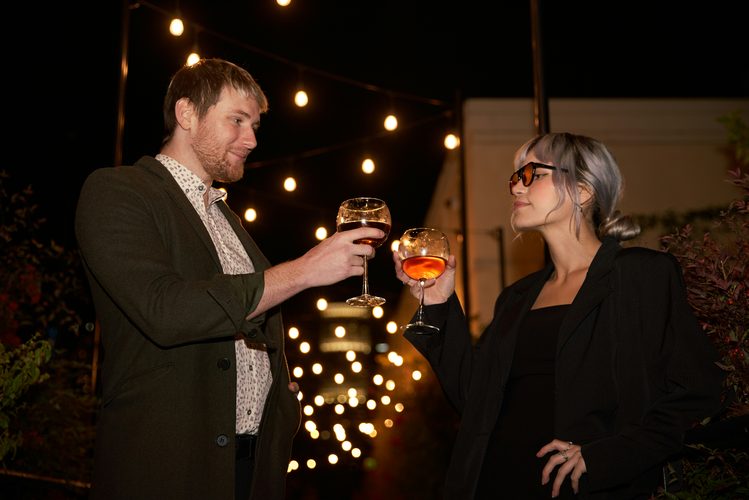 Couple toasting cocktails outdoors at night